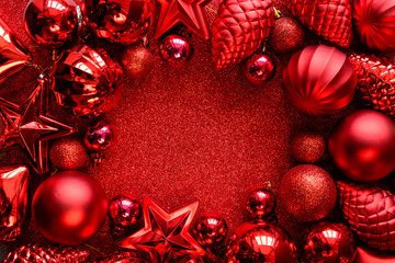 Red Christmas frame. Christmas balls, stars, cones and hearts on red sparkles background. Flat lay. Top view. Copy space