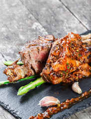 Grilled pork steaks with herbs, asparagus, garlic, mushrooms and potato fry on stone slate background on wooden background close up. Hot Meat Dishes. Top view, flat lay
