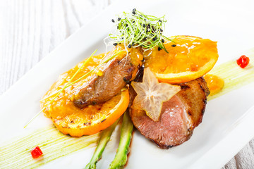 Grilled pork chop steak chargrilled to medium rare with orange sauce on wooden background. Hot Meat Dishes. Top view