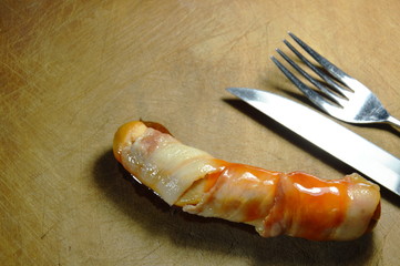 bacon roll pork sausage dressing ketchup and chili sauce on wooden chop block