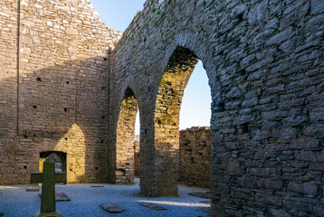 Stone cross within the old ruin walls of  12th Century Irish monastery. Corcomroe Abbey, tourist attraction in County Clare, Burren, Ireland.