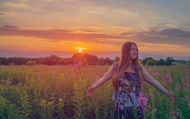 Obraz premium Beautiful girl smiling in a field of sunset