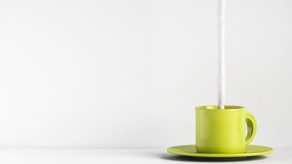 Milk being poured in green coffee cup