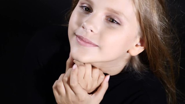 Pretty little model posing in studio isolated on black. White - haired girl looks at camera, smiling, 4k