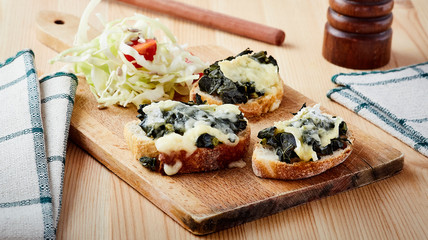 three cabbage and cheese bruschetta on wood board on table with salad