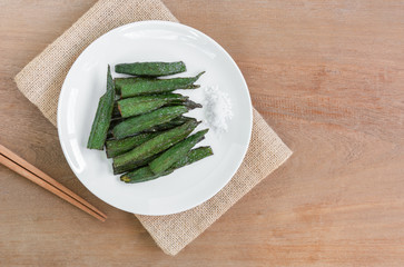 top view of fried okra in a ceramic dish on wooden table. homemade style healthy food concept.