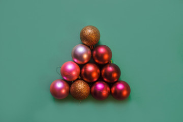 Christmas tree made by gold, red and pink Christmas balls on the green background, copy space