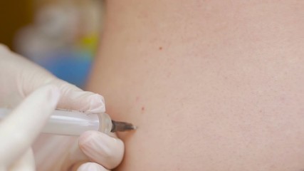 Close-up of the hand of a medic administering an intramuscular injection to a patient.
