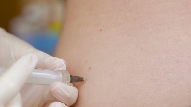 Close-up of the hand of a medic administering an intramuscular injection to a patient.