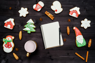 Homemade gingerbread cookies, cup of cocoa and open blank notebook on dark wooden table. Top view, flat lay. Christmas background with santa, snowman, snowflake, stocking, fir tree, copy space
