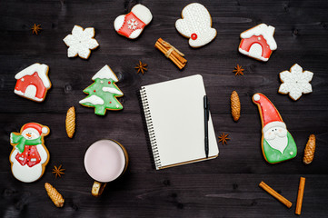 Obraz na płótnie Canvas Homemade gingerbread cookies, cup of cocoa and open blank notebook on dark wooden table. Top view, flat lay. Christmas background with santa, snowman, snowflake, stocking, fir tree, copy space