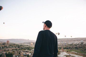 A man in solitude admires a beautiful view of the flying balloons in Cappadocia in Turkey.
