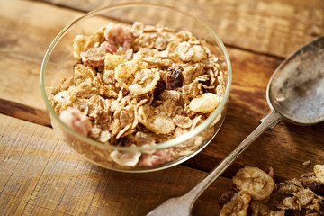 Healthy morning breakfast bowl full of organic granola with a rustic spoon on an old wooden table