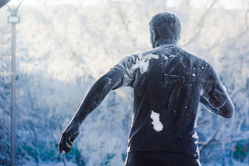 A rear view of the frozen monumet of footballplayer against blue background in winter © Ann Marko