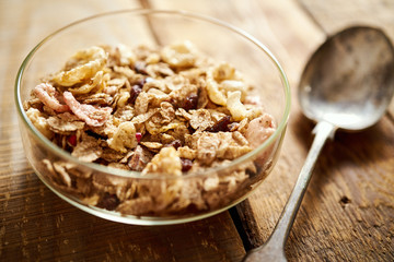 Healthy morning breakfast bowl full of organic granola with a rustic spoon on an old wooden table