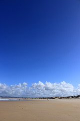 blue sky and clouds in the background, sand and people