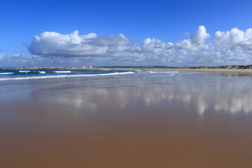 Obraz premium Peniche beach with sky and white clouds reflected in the sand