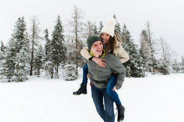 Fototapeta na wymiar Love couple on winter holiday. Woman riding piggyback