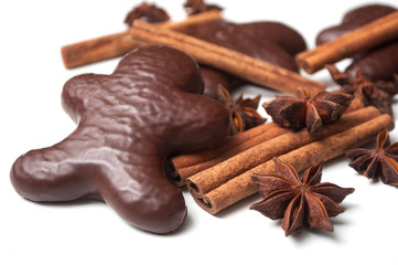 closeup of christmas gingerbread chocolate coated biscuit in shaped man with anise flower and cinnamon stick on white background