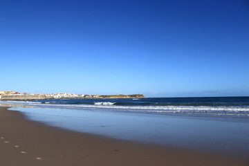 Fototapeta na wymiar beach with sky reflections in the sand on blue