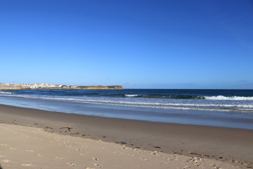 beach with wet sand and city in the background