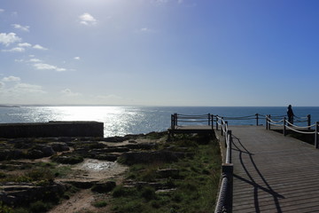 Fototapeta premium man looking at the sea in the belvedere with the sun reflecting in the sea silver color