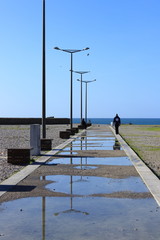 man walking on the side of the promenade flooded toward the sea