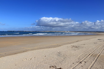 Sand in the foreground, blue sea and cloudy sky in the background, Gâmboa beach