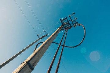 Power lines on background of blue sky close-up. Electric hub on pole. Electricity equipment with...
