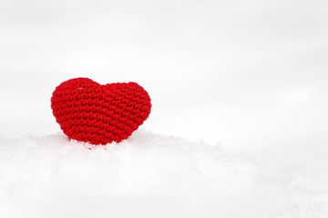 Fototapeta premium Red knitted heart in the snow, Valentine's day background. Symbol of romantic love, concept of blood donation, snowfall, Christmas mood