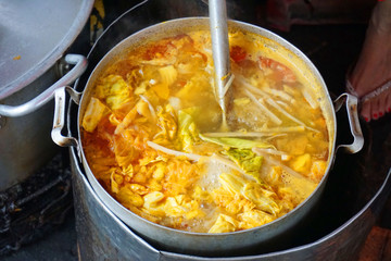 Delicious colorful soup stock with tomato slices pork potato tofu cabbage chilly sauce yellow color steamed meat stock for fish cake noodles Vietnamese traditional food Asian cuisine street food