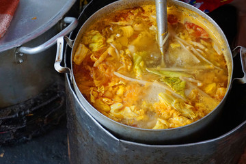 Delicious colorful soup stock with tomato slices pork potato tofu cabbage chilly sauce yellow color steamed meat stock for fish cake noodles Vietnamese traditional food Asian cuisine street food
