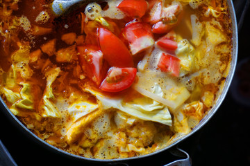 Delicious colorful soup stock with tomato slices pork potato tofu cabbage chilly sauce yellow color steamed meat stock for fish cake noodles Vietnamese traditional food Asian cuisine street food