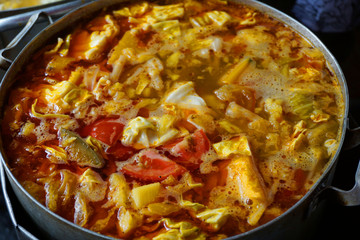 Delicious colorful soup stock with tomato slices pork potato tofu cabbage chilly sauce yellow color steamed meat stock for fish cake noodles Vietnamese traditional food Asian cuisine street food