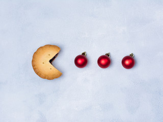 Retro game cookies with red Christmas bauble decoration on concrete blue background. Creative New Year minimal concept.