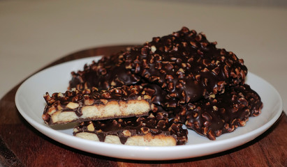 Chocolate square biscuits with nuts on a white round plate. Tea sweets
