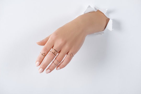 cropped image of woman holding hand with beautiful luxury silver rings through white paper