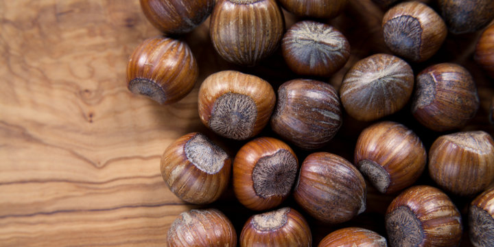 whole hazelnuts in shell with olive board - copy space on wooden board. Hazelnuts are good source of protein, healthy snack and are important for a healthy, balanced, vegan and plant based diet. 