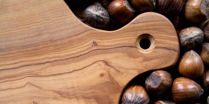 Olive board with hazel nuts in shell - copy space on wooden board. Hazelnuts are good source of protein, a healthy snack, part of a healthy, vegan and plant based diet.