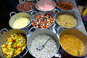 delicious various colorful sweet dessert from coconut cream shredded with glutinous rice and pandan black red beans Asian cuisine traditional street food in metal pans 