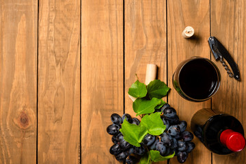 Wine bottle cups bunches of grapes and cork stopper on wooden background. Top view with copy space