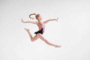 Fototapeta na wymiar Llittle girl gymnast, performs various gymnastic and fitness exercises. A healthy lifestyle.