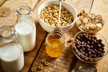 Healthy morning breakfast with different types of breakfast cereals with a spoon, honey and milk on an old wooden table