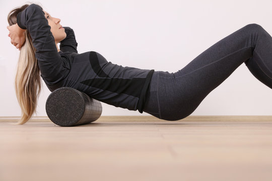 Woman doing balance foam roller exercises. Mindful workout holistic health care.
