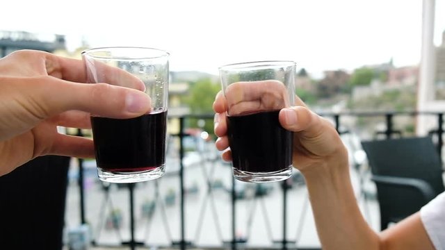 Two glasses of wine clink glasses on a date in a restaurant, slow motion