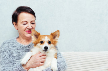 Portrait of senior woman holding her dog on sofa