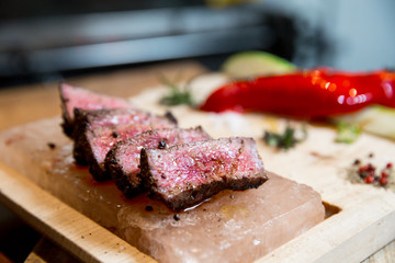 Juicy medium Beef Rib Eye steak slices in pan on Himalayan pink salt plates.