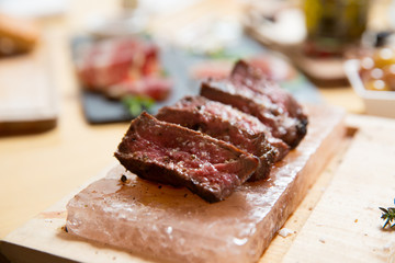 Juicy medium Beef Rib Eye steak slices in pan on Himalayan pink salt plates.