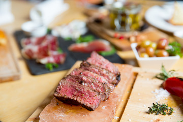 Juicy medium Beef Rib Eye steak slices in pan on Himalayan pink salt plates.