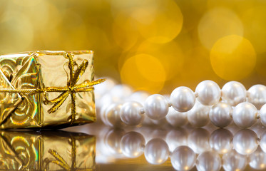 Fototapeta na wymiar Christmas card background - gold gift box with white pearls, women shopping